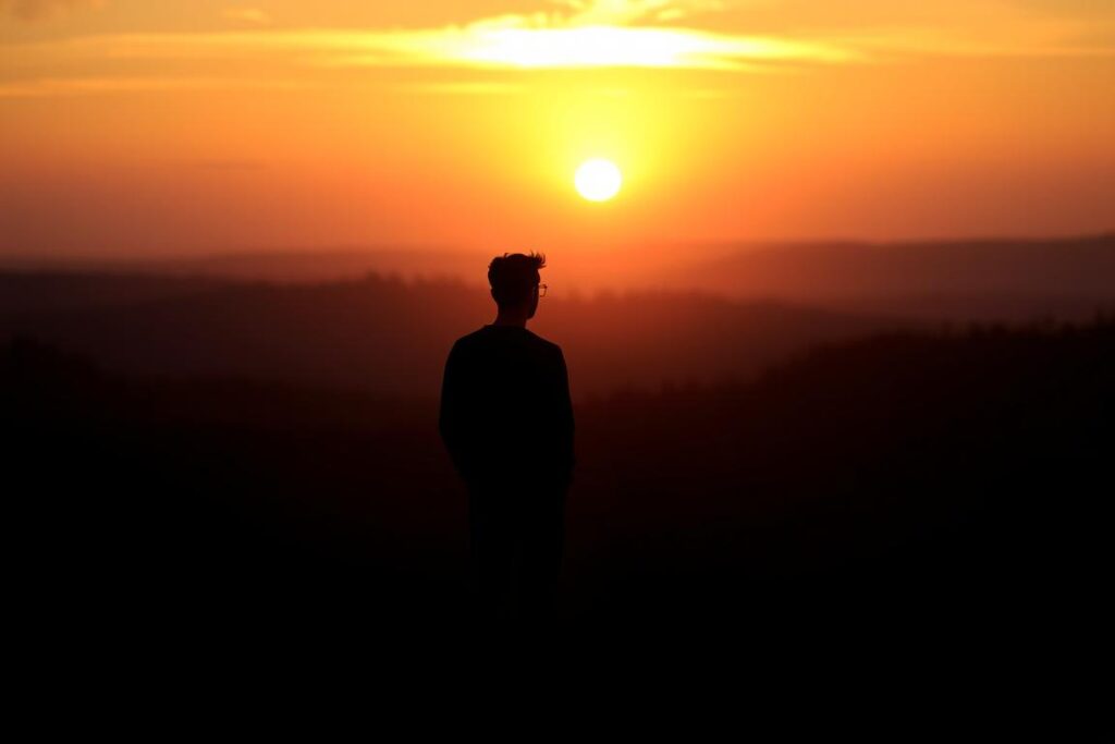 Persoană privind spre apus, siluetă contemplativă, reprezentând reflecția asupra viitorului relației după trădare